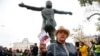 Russia -- An opposition activist holds the Russian Constitution book in front of the monument to Soviet-era opposition legendary bard Vladimir Vysotsky during a protest in the center of Moscow, Russia, Saturday, Aug. 17, 2019