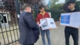 Кымбат Абеуулы (в центре) и Таскын Кудайберген разговаривают с представителем посольства Казахстана во время акции протеста у здания посольства в Амстердаме